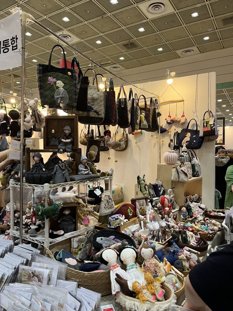 Handmade dolls, quilted bags, and textile crafts displayed by an artisan vendor at Handarty Korea in Seoul.