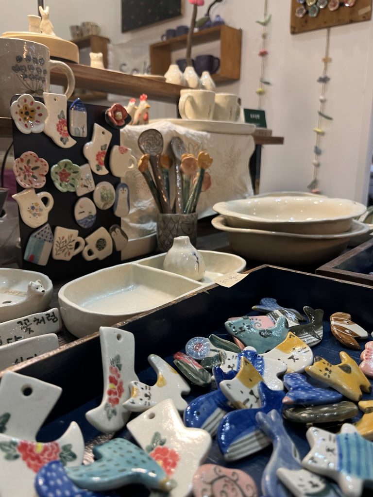 Handmade ceramic magnets, dishes, and pottery displayed by a Korean artisan at Handarty Korea.