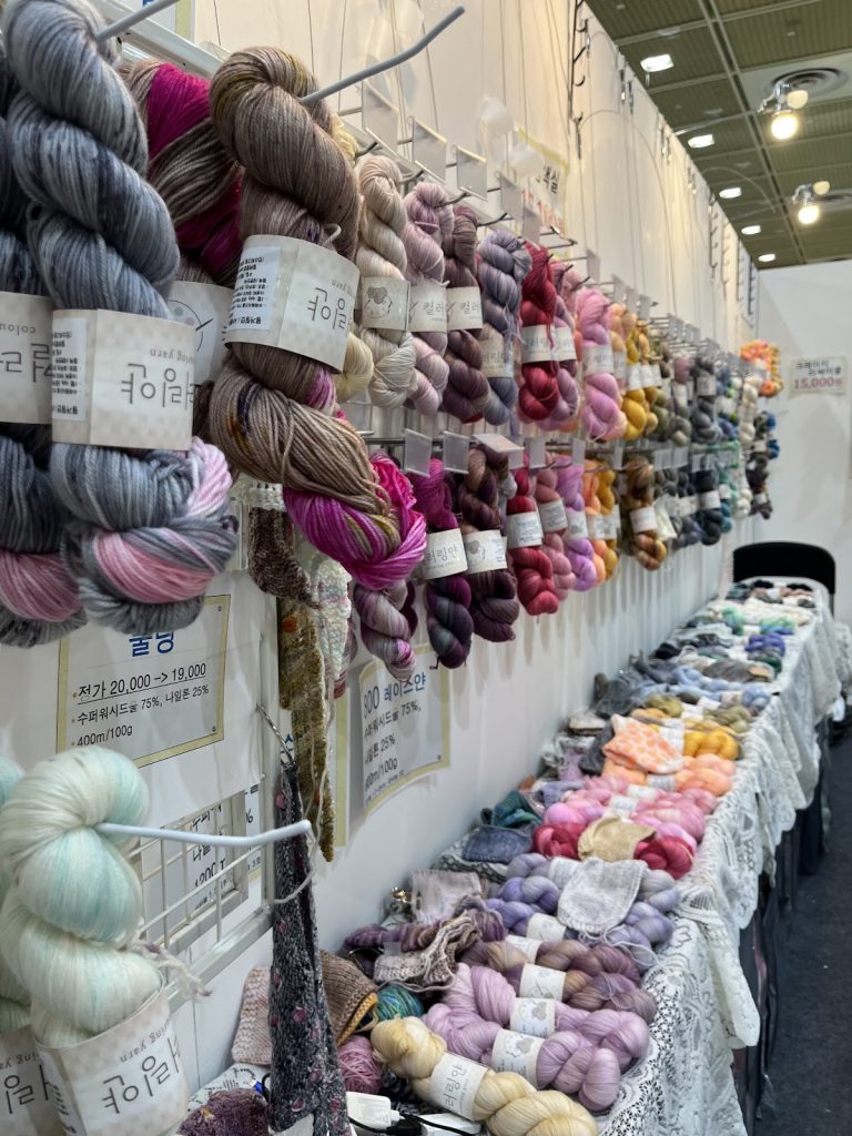 Colorful hand-dyed yarn and knitted fiber art displayed at a vendor booth during Handarty Korea.